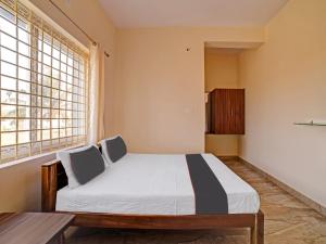 1 dormitorio con cama, mesa y ventana en OYO Hotel Rajaganga Lodge en Hassan
