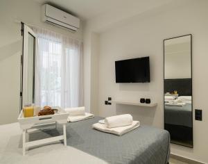 a white room with a bed and a television at Noema Urban Living in Heraklio