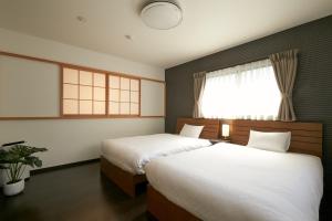 a bedroom with two beds and a window at Kyo no yado BOTAN in Kyoto