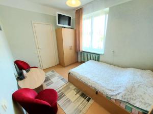 a bedroom with a bed and two red chairs at Neringos 8 in Palanga
