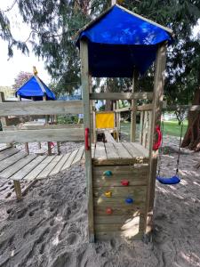 une structure de jeu sur le sable avec une canopée bleue dans l'établissement Appartementhaus Brunsholm, à Esgrus