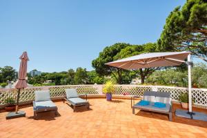 eine Terrasse mit 2 Stühlen und einem Sonnenschirm in der Unterkunft Villa Vale Do Lobo 626 - 3 Bedroom villa - Great pool area - Perfect for families in Vale do Lobo