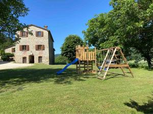 a playground in a yard with an old building at Agriturismo Popolano Di Sotto in Marradi