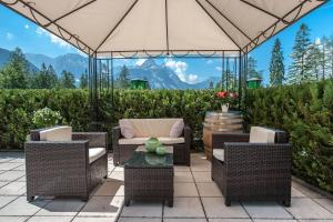 a patio with wicker chairs and an umbrella at Zugspitzhotel Diana Thörle in Ehrwald