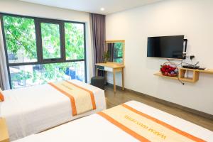 a hotel room with two beds and a flat screen tv at Warm Ways Hotel & Serviced Apartments in Ho Chi Minh City