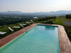 a swimming pool with chairs and a view of the mountains at Agriturismo Mansi Bernardini in Lucca
