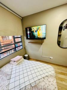1 dormitorio con TV de pantalla plana en la pared en Prívate room close to the Dorado AirPort Bogota, en Bogotá