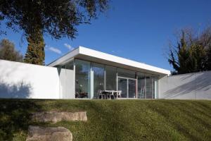 a white house with glass doors on a grass field at Casa Briteiros in Guimarães
