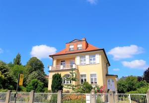 uma casa amarela com um telhado vermelho em VILLA FREIA Dresden - Exklusive Ferienwohnung zum Erholen & Entspannen em Dresden