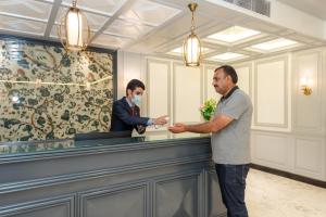 a man standing at a bar with a man wearing a mask at Hotel Grand Boulevard Dal Lake View Srinagar in Srinagar +33 photos