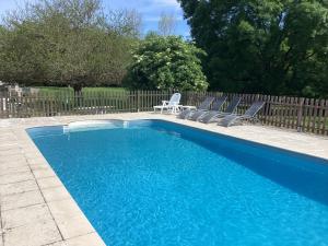 una piscina azul con sillas y una valla en Le Petit Bijou en Saint-Fraigne