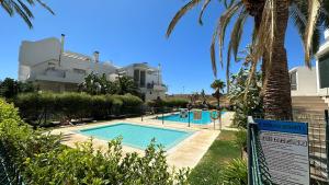 a swimming pool in front of a house with palm trees at Vitania Resort La Cala Apartment in Málaga
