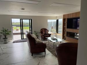 a living room with two chairs and a tv at Bijou Apartment in Spanish Point in Spanish Point
