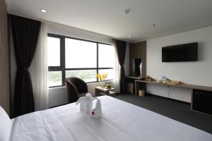 a hotel room with a bed and a television at Pearl Beach Hotel Quy Nhon in Quy Nhon