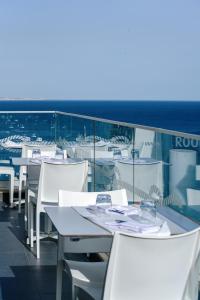 a row of tables and white chairs on a balcony at Carvi Beach Hotel in Lagos