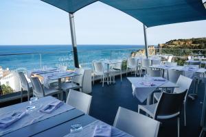 a restaurant with white tables and chairs and the ocean at Carvi Beach Hotel in Lagos