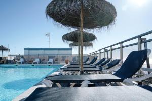 a group of chairs and umbrellas next to a swimming pool at Carvi Beach Hotel in Lagos