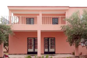 ein rosafarbenes Haus mit Balkon darüber in der Unterkunft Olivenparadies in Heddad