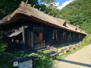 una casa antigua con techo de paja y bancos delante en 玉川温泉の湯治に最適な宿　鳳凰館, en Senboku