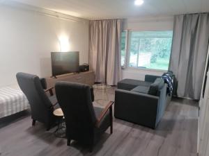 sala de estar con sofá, sillas y TV en Majoituspalvelu Nurmi Apartment Peipontie 3 B, en Raahe