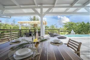 einem Holztisch mit Tellern und Gläsern darüber in der Unterkunft Villa Verde - Les Terres Basses in Marigot