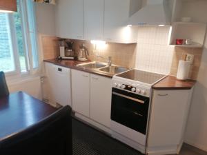 cocina con armarios blancos, fregadero y fogones en Majoituspalvelu Nurmi Apartment Peipontie 3 B en Raahe