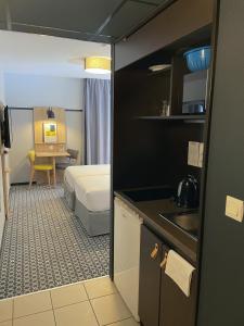 リヨンにあるOdalys City Lyon Bioparcのベッドルーム1室(ベッド1台付)、キッチンが備わります。
