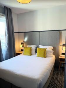ein Hotelzimmer mit einem großen Bett mit gelben Kissen in der Unterkunft Odalys City Lyon Bioparc in Lyon