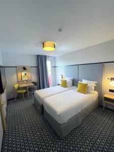 ein Hotelzimmer mit 2 Betten und einem Schreibtisch in der Unterkunft Odalys City Lyon Bioparc in Lyon