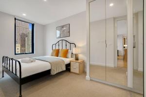 1 dormitorio con 1 cama y pared de cristal en Bright 2B apt next to Flagstaff Garden freeparking#FG1003, en Melbourne