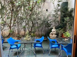 a patio with two tables and blue chairs and a statue at Bue Hotel in Buenos Aires