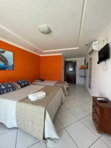 Barra de Tabatinga的住宿－Praia das Tartarugas，橙色墙壁客房的两张床