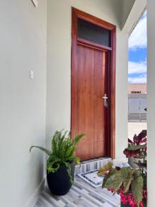 eine Holztür in einem Haus mit Topfpflanzen in der Unterkunft Dodoma Home Apartments in Dodoma