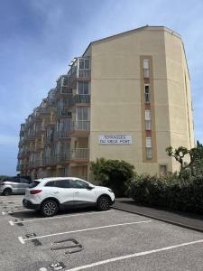 un coche blanco estacionado en un estacionamiento frente a un edificio en studio 3 personnes accès direct plage - parking privé - 3TVP30, en Le Barcarès