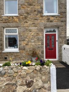 a brick house with a red door and a stone wall at Carn View Located Nr Heartlands & Carn Brea in Pool
