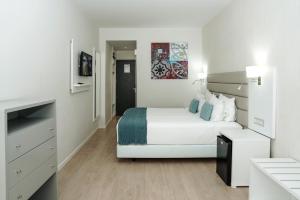 a white bedroom with a bed and a tv at Carvi Beach Hotel in Lagos