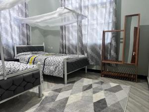 1 Schlafzimmer mit 2 Betten, einem Spiegel und Vorhängen in der Unterkunft Dodoma Home Apartments in Dodoma