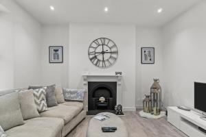 a living room with a couch and a clock on the wall at The Grenville - Stunning Spacious Central Plymouth Apartment - Sleeps 4 in Plymouth