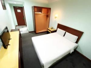 een slaapkamer met een bed en een tv. bij OYO 90847 Hotel Asia City in Kota Kinabalu