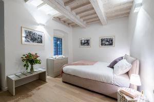 a white bedroom with a bed and a table with flowers at Fiordaliso Boutique Apartments in Florence