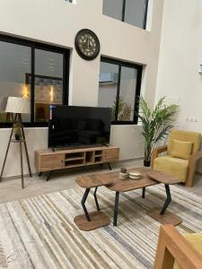 a living room with a television and a coffee table at شاليهات النرجس in Obhor