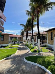 a walkway in front of a building with palm trees at Praia das Tartarugas in Barra de Tabatinga