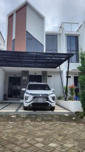 une voiture blanche garée devant un immeuble dans l'établissement CMI Homestay, à Tlekung