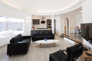 a living room with black leather furniture and a table at 4 bedroom Villa Mimi with private heated pool in Puerto del Carmen