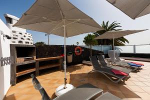 a patio with chairs and an umbrella on a roof at 4 bedroom Villa Mimi with private heated pool in Puerto del Carmen