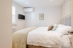 a white bedroom with a bed with white walls at Luxury flat on Fulham/Chelsea border in London
