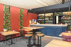 a bar with wooden tables and chairs in a restaurant at Hôtel des Voyageurs in Bagnols