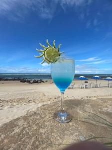 a glass of blue drink with a lime on the beach at Praia das Tartarugas in Barra de Tabatinga