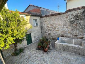 a stone building with potted plants in a courtyard at Casa do Compasso in Farminhão