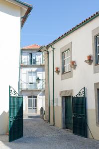 a building with a green gate in a street at Casa do Compasso in Farminhão